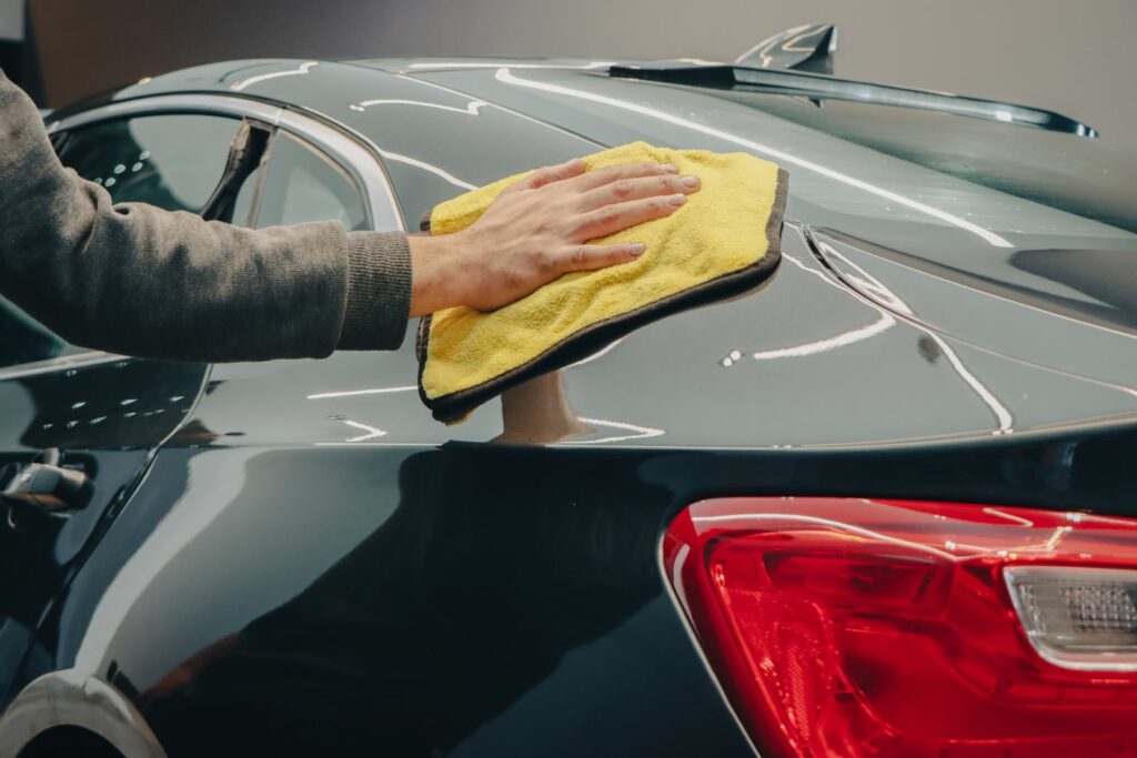Application d’une cire voiture au chiffon microfibre sur une carrosserie brillante