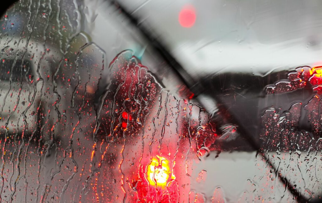 Traitement hydrophobe pare-brise : gouttes d'eau perlant sur un pare-brise sous la pluie